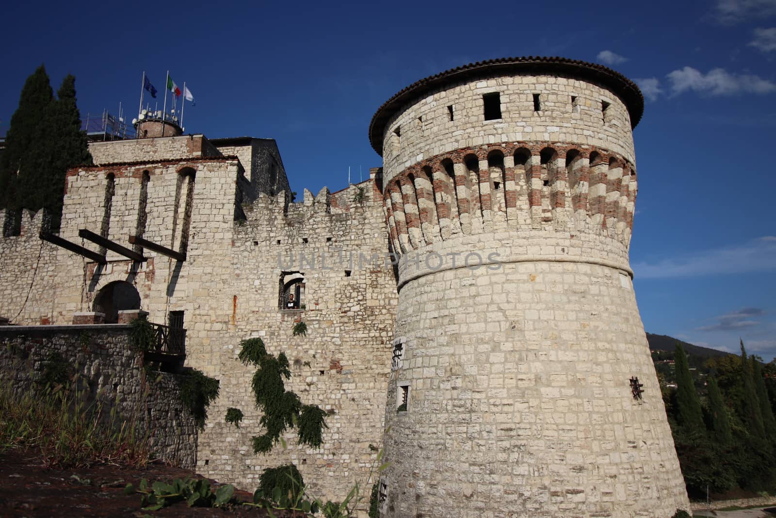 Stone wall with merlons and drawbridge gate of medieval castle of Brescia in north Italy