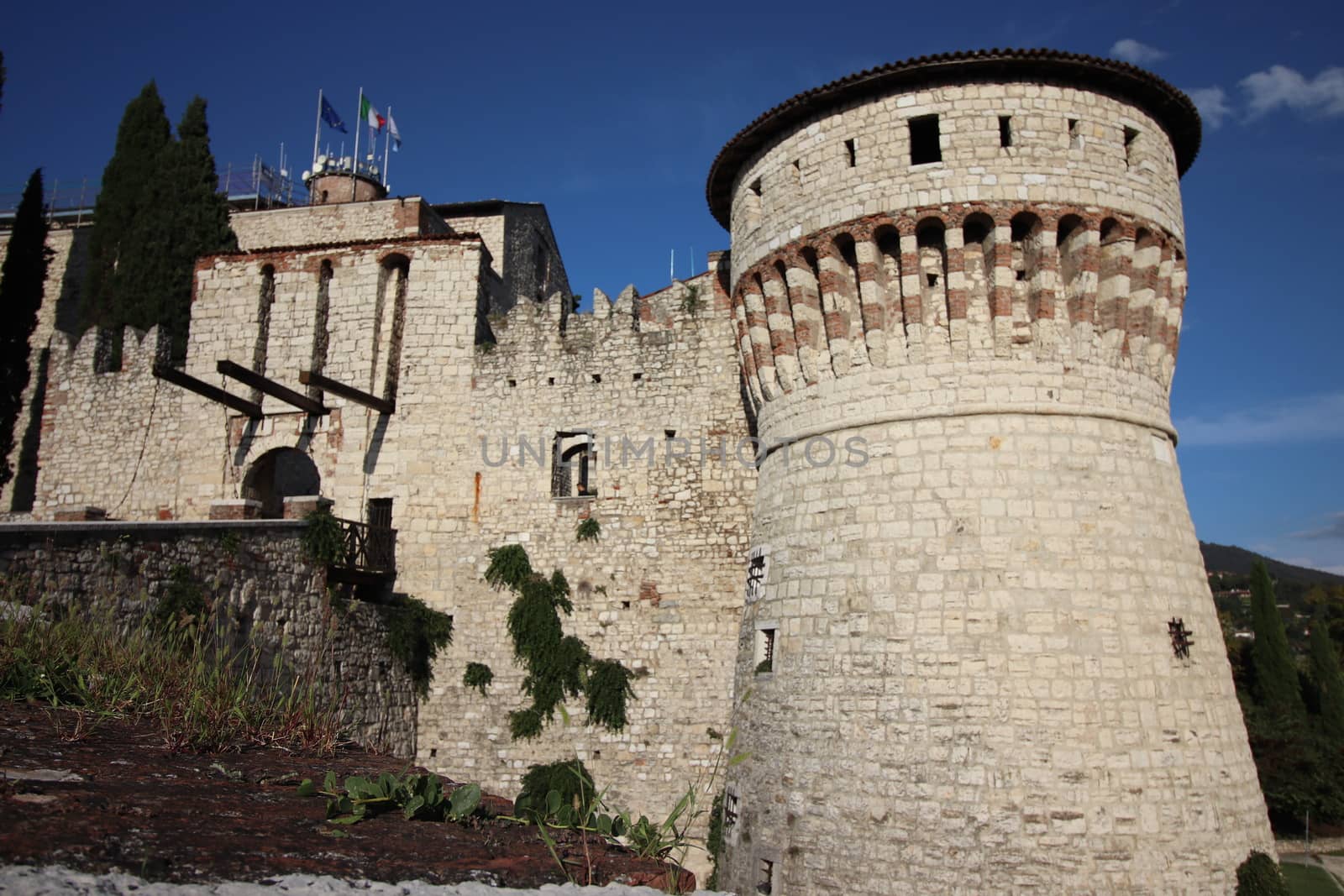 Stone wall with merlons and drawbridge gate of medieval castle of Brescia in north Italy