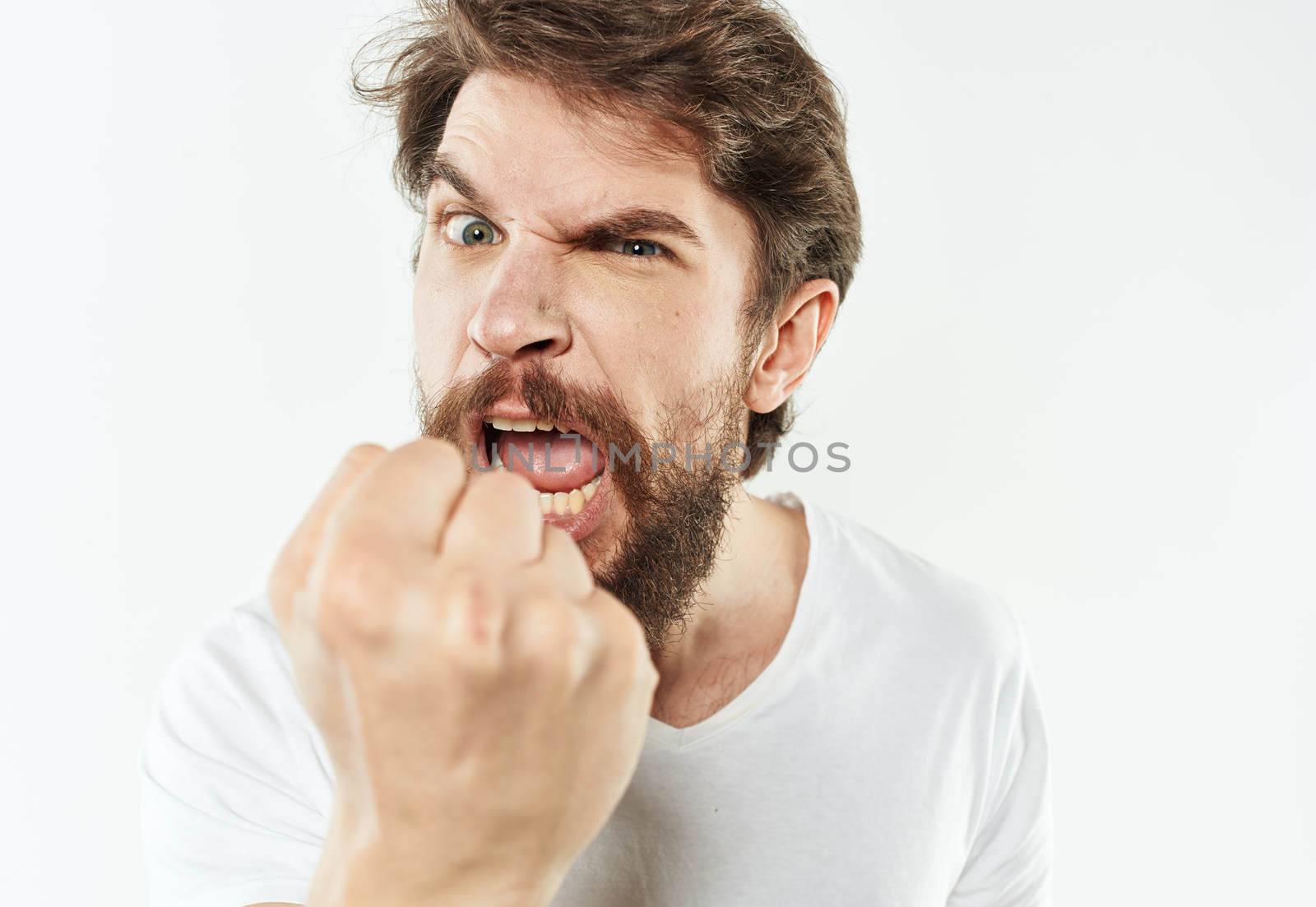 Angry man in a white t-shirt shows a fist gesturing with his hands to the model by SHOTPRIME