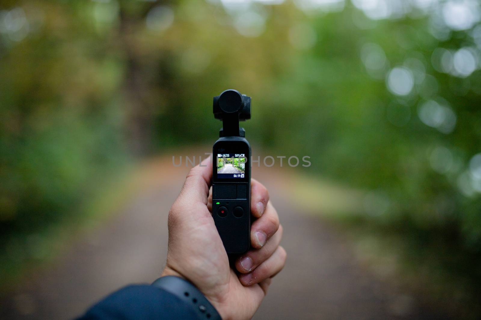 London, UK - December 1, 2018: Landscape View of a Hand Holding an DJI Osmo Pocket Camera Gimbal Recording the Blurry Forest in the background
