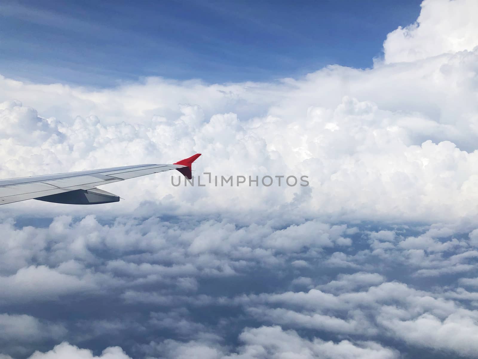 Wing of airplane flying above cloud