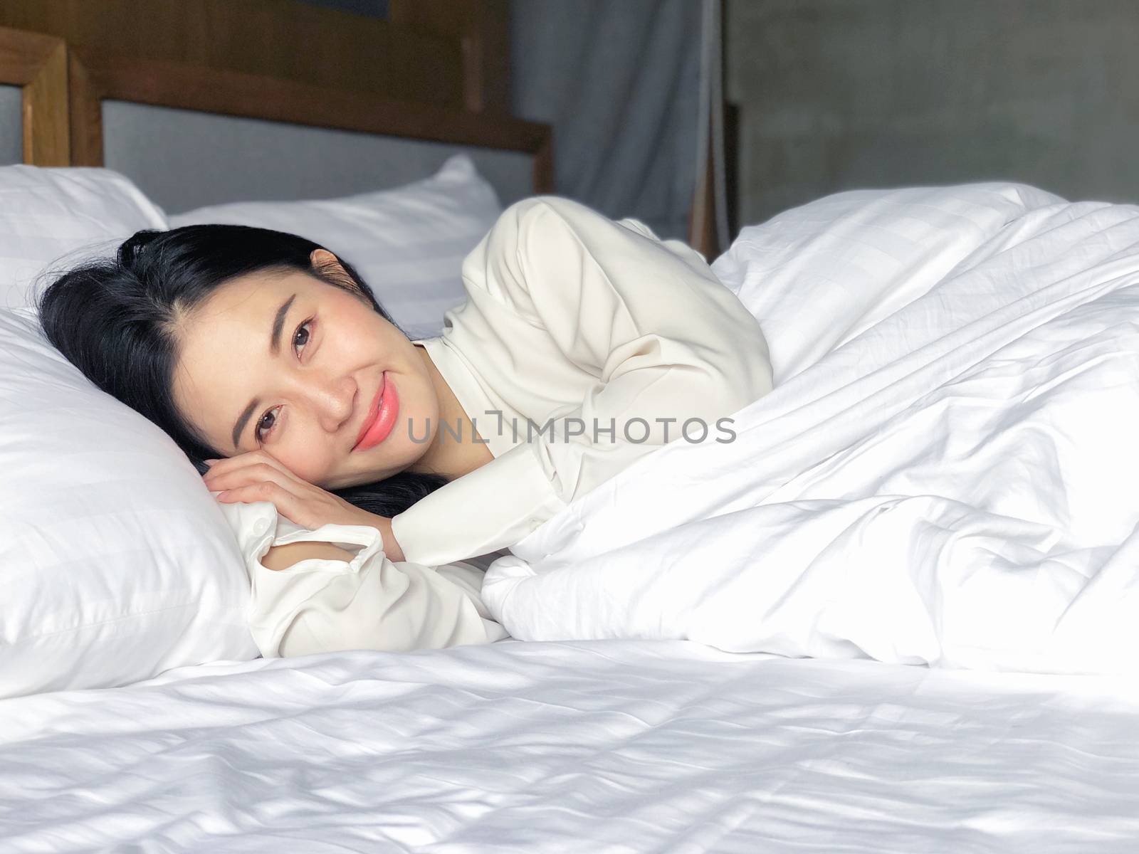 Beautiful Asian woman sleeping in bed under white quilt with head on pillow comfortable and happy. girl with relax for health concept.