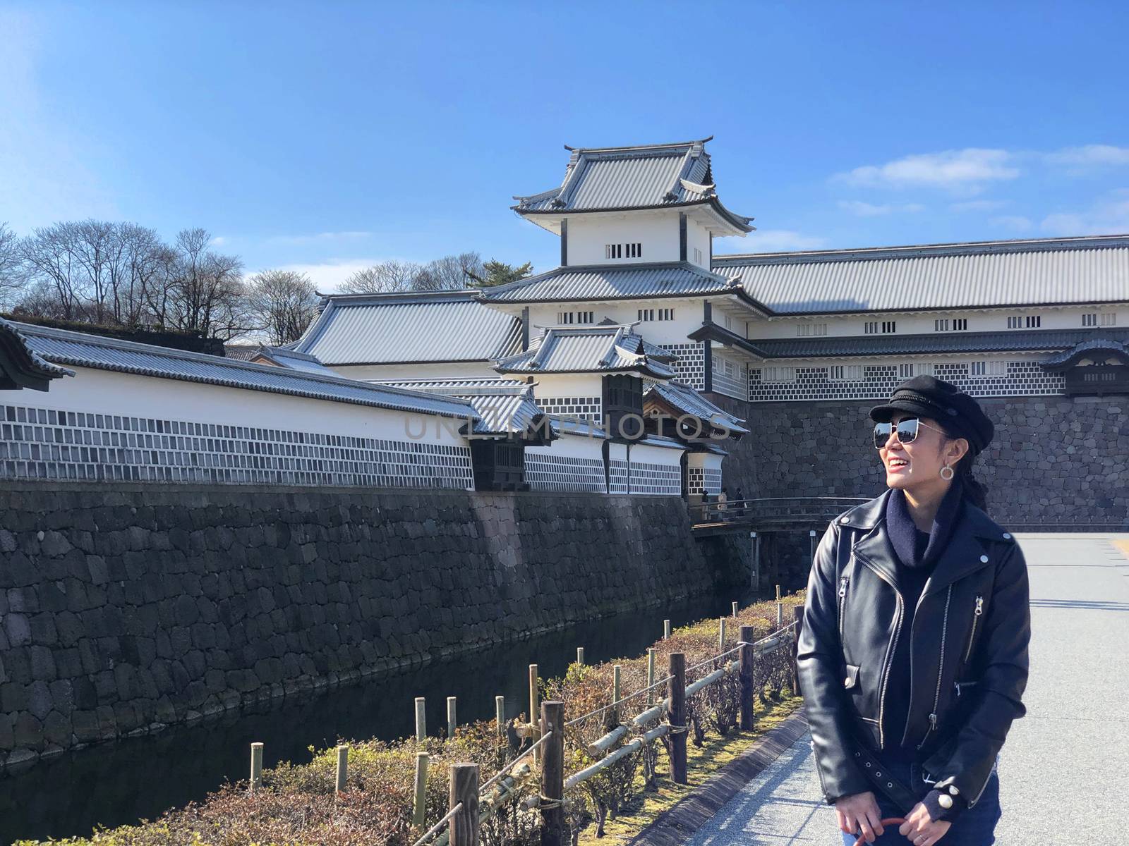 Young tourist woman smiling and enjoying beautiful view of Kanazawa Castle in Japan 