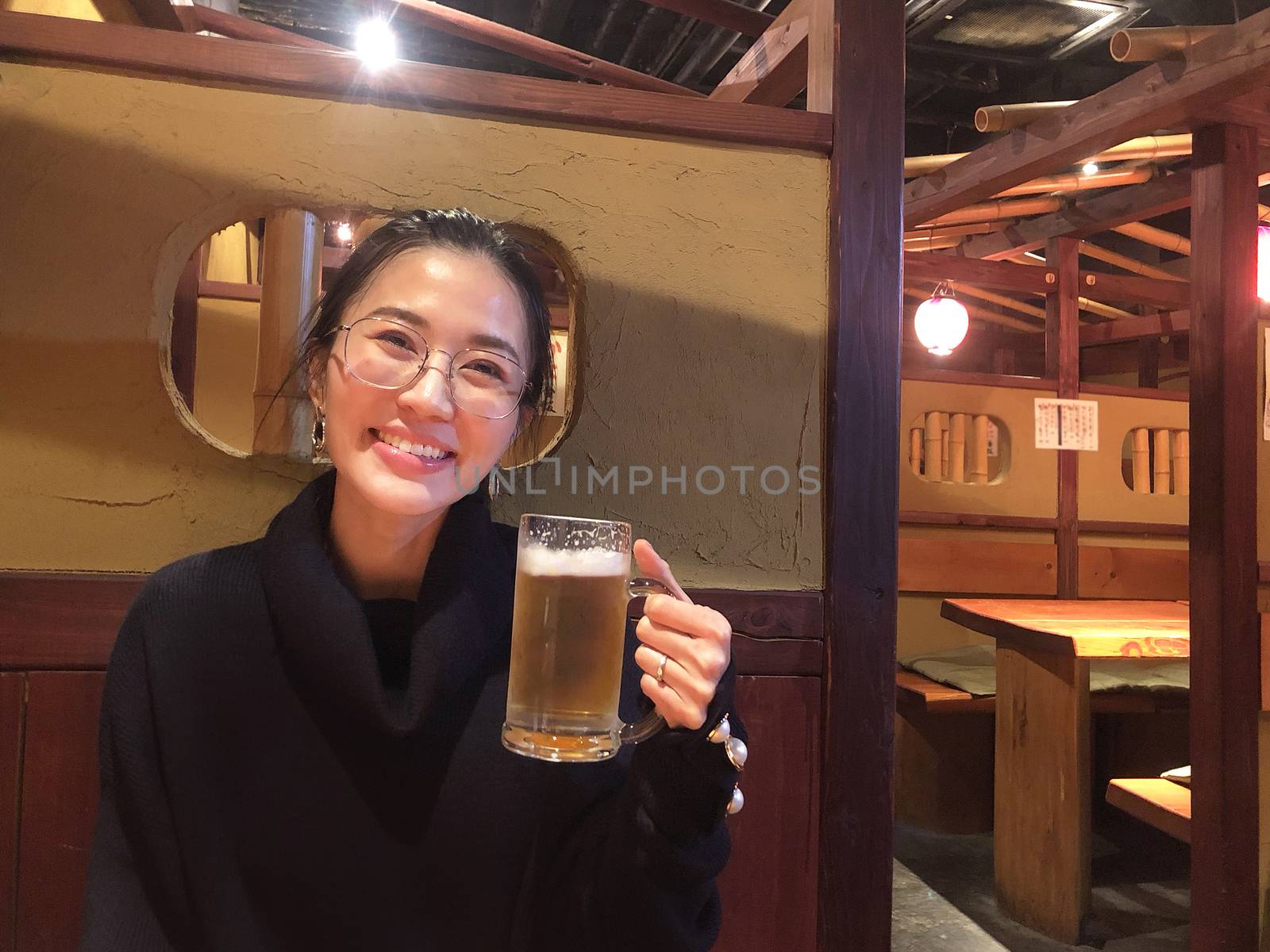 Happy smiling woman enjoy eating beer at classic restaurant in J by Surasak