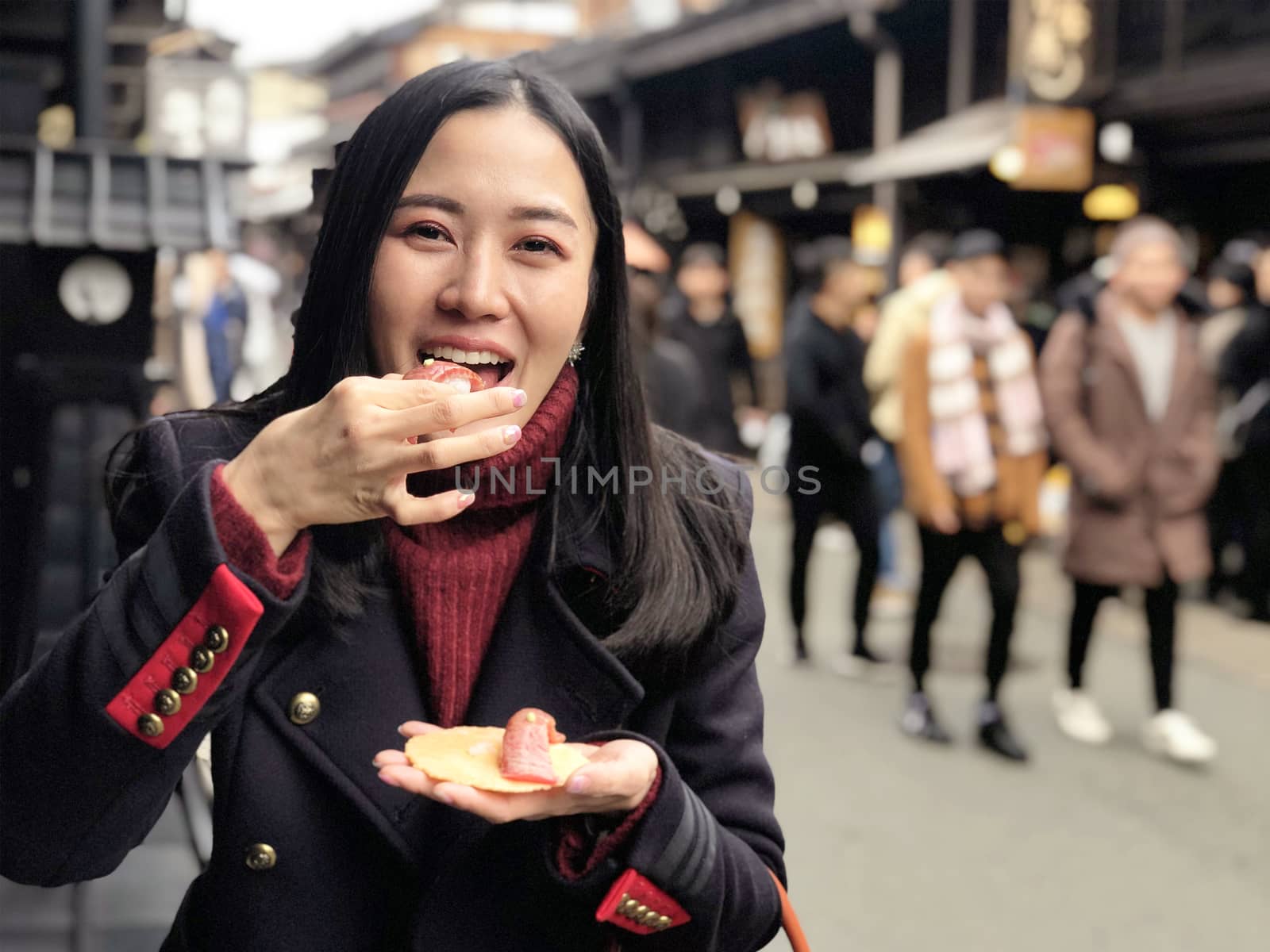 Young woman tourist enjoy eating Japanese street food Hida Beef  by Surasak