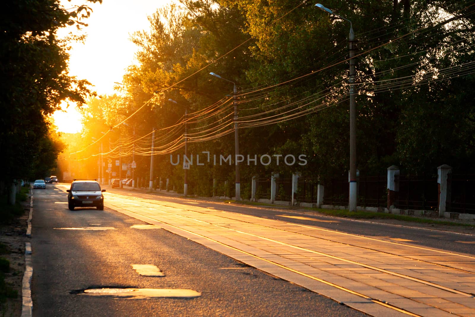 TULA, RUSSIA - JUNE 6, 2013: Car on city street under golden sun backlight. Dust in the air volumetric glowing bright.