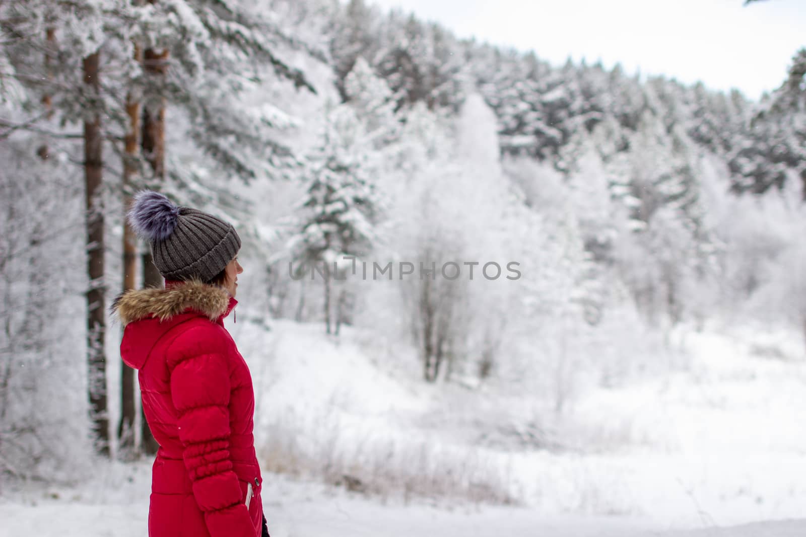 A young woman in a red jacket in a winter forest. Winter and frosty forest in the mountains. Nature walk