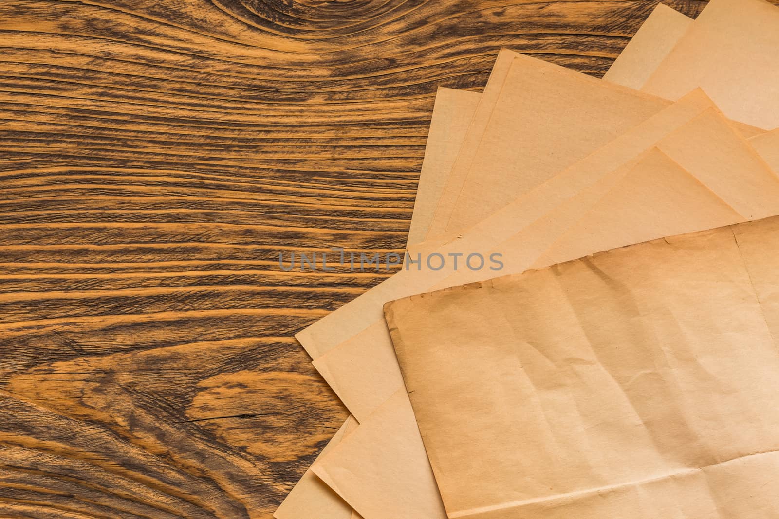 sheets of old yellow paper on wooden table surface