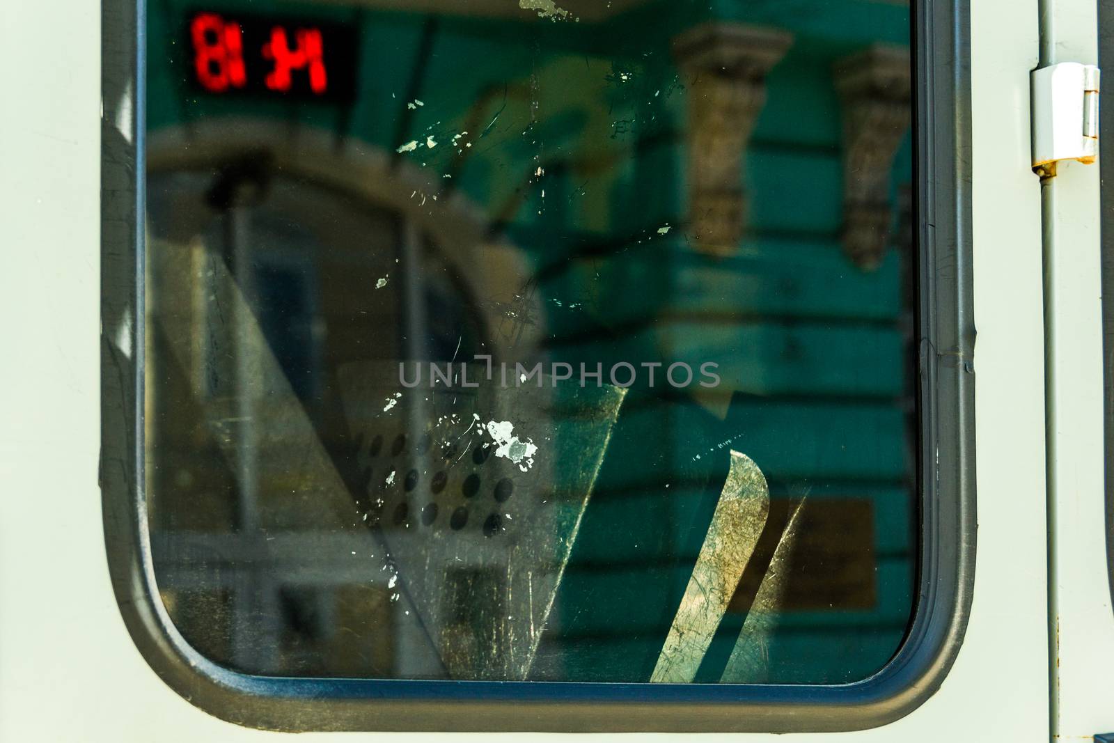 Police shields inside van window with green architecture and public red digital clock reflection 