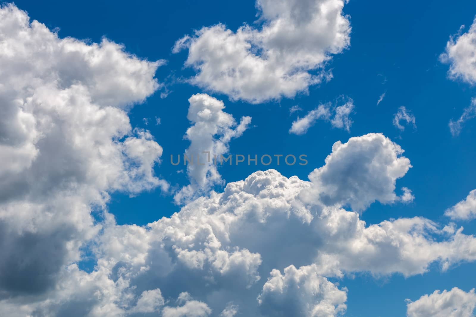 white c cumulus clouds on blue sky background telephoto view