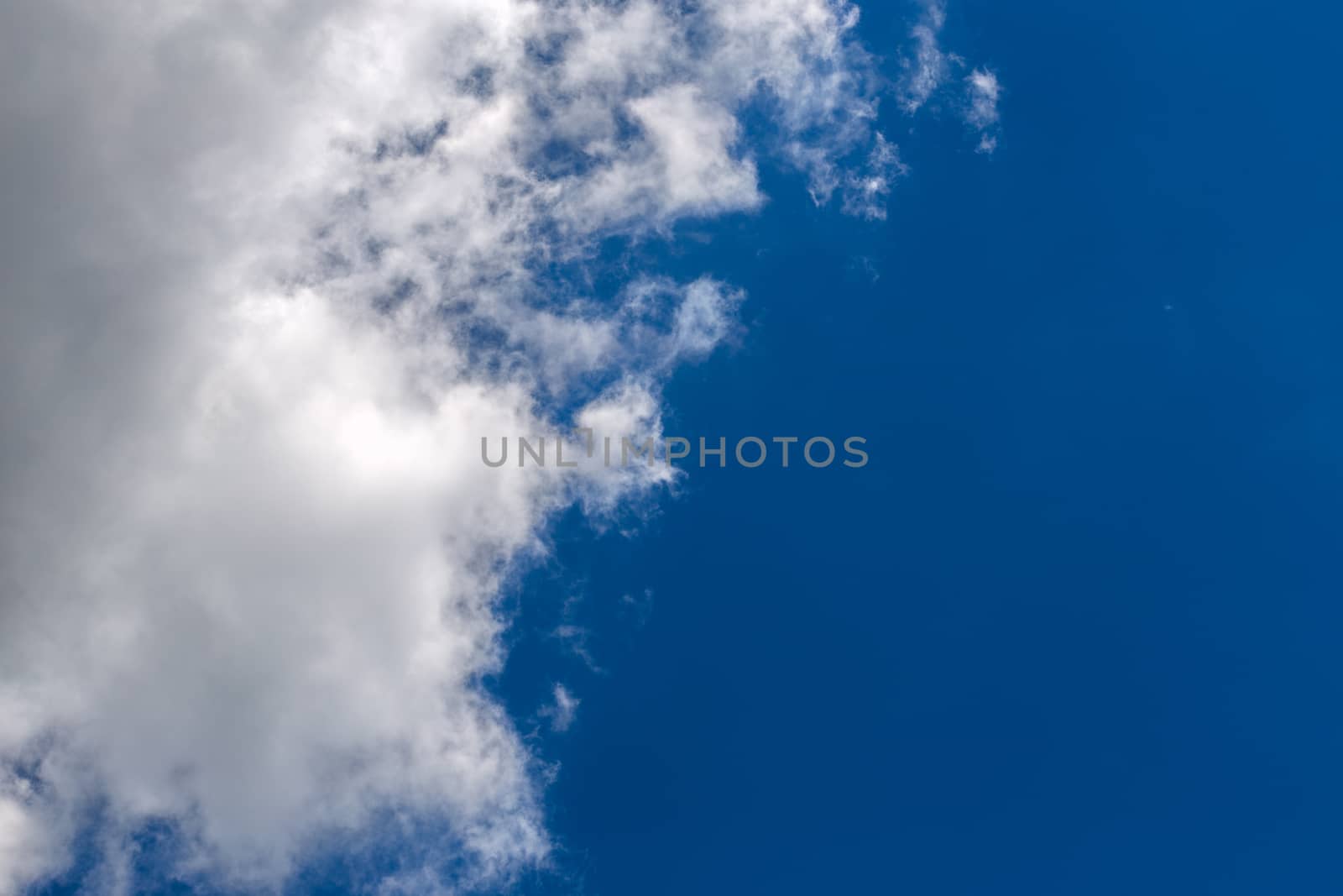 white c cumulus clouds on blue sky background telephoto view