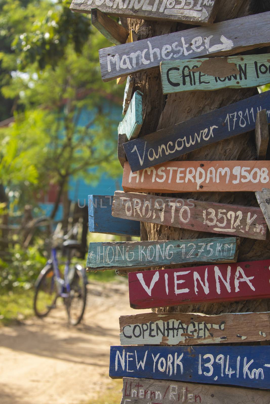 Colourful hand painted direction wood signs to different cities of the world, and mileage marker in Don Det island, one of the famous Four Thousand Islands or Si Phan Don, in the Mekong river, Laos.