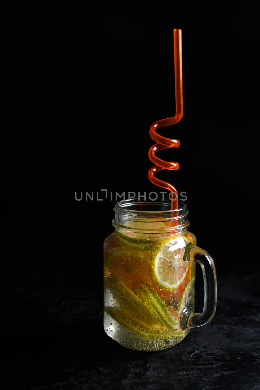 Fresh citrus lemonade in a jug isolated on black background by sashokddt