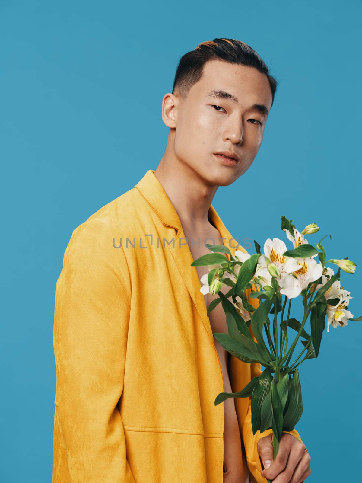 A cute guy of Asian appearance holding a bouquet of white flowers cropped view portrait. High quality photo