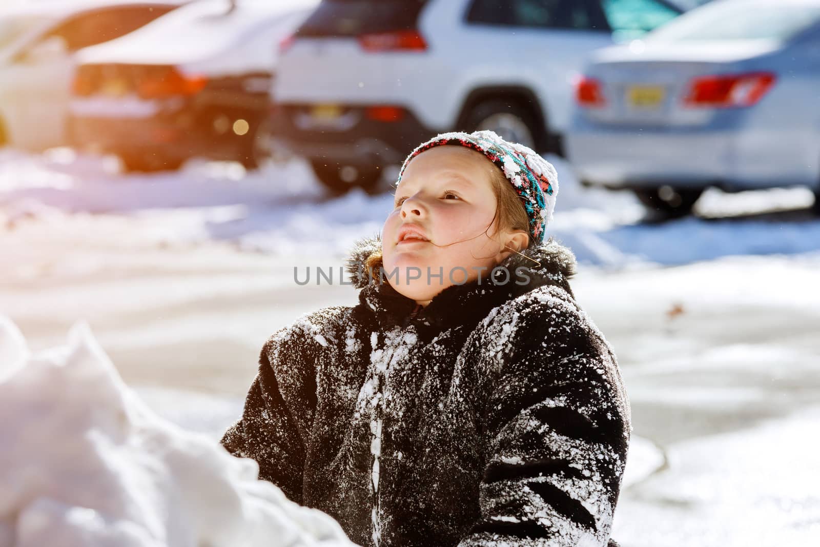 Beautiful happy little kid play with snow in a snow on home drive way