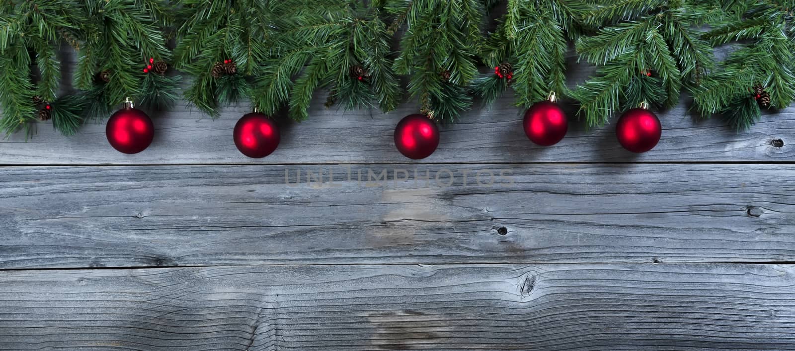 Christmas rustic natural wooden background with evergreen branches and red ball ornaments  