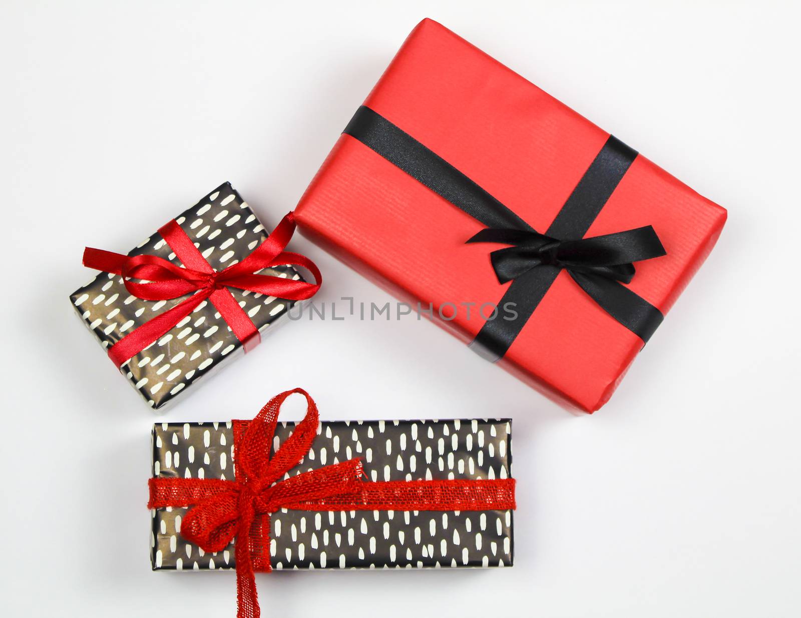 Gifts wrapped with colorful paper and red and black bows on white background