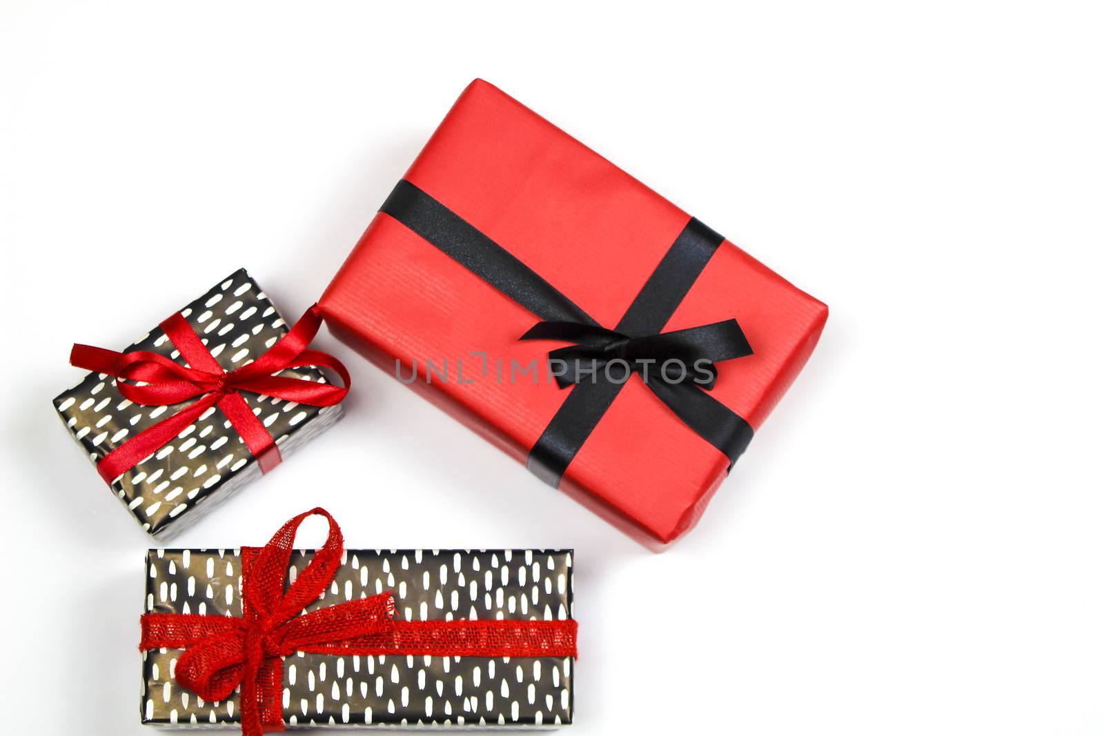 Gifts wrapped with colorful paper and red and black bows on white background