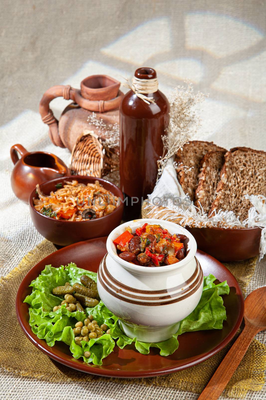 Bread, greenery and ceramic vases on a canvas background