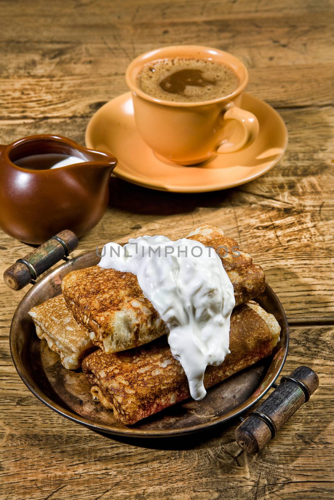 Pancakes with cream on a wooden table