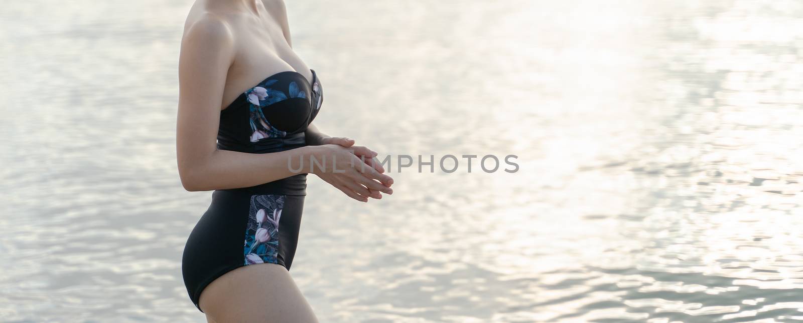 Body part of woman in one piece swimsuit on the beach. Relaxing by sirawit99