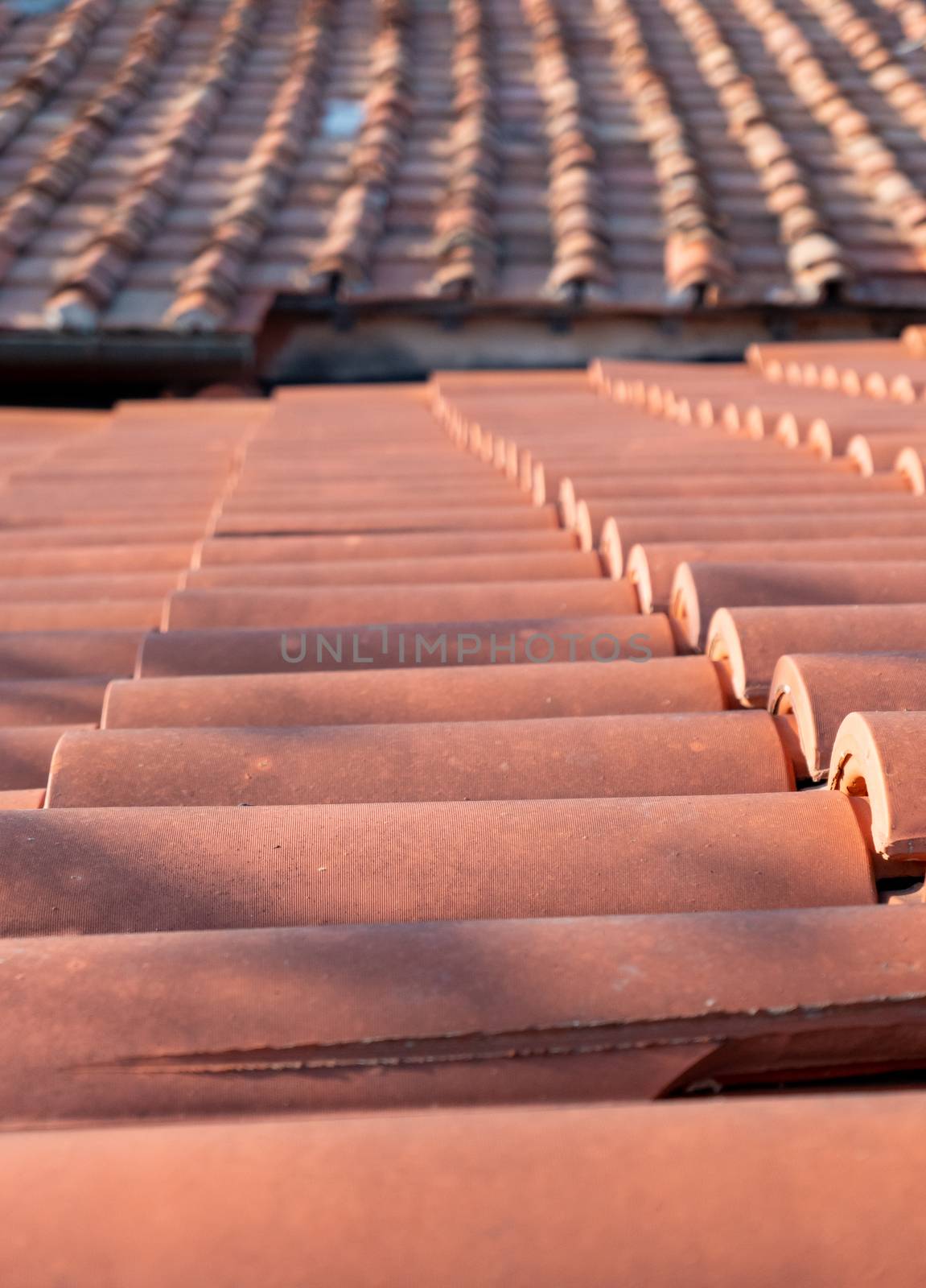 Two flat tiled roofs, photographed flat, one of which is covered with new red tiles and one with old red tiles