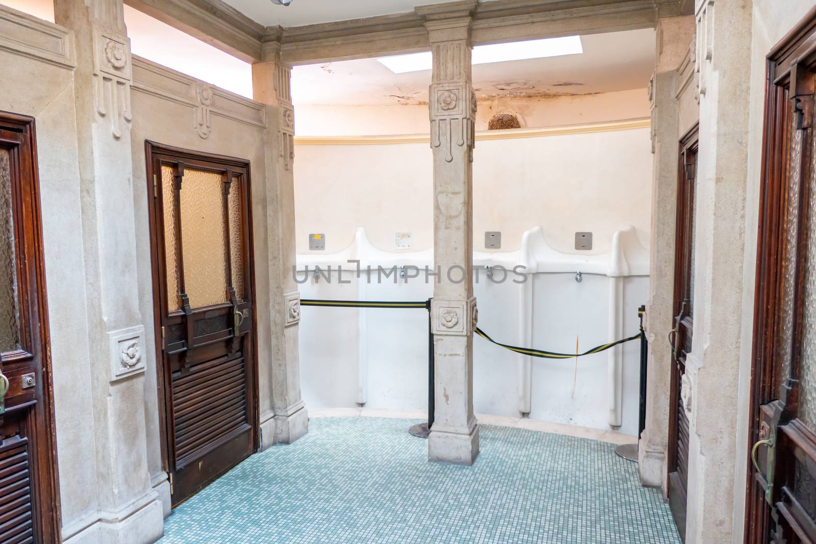 Verona, Veneto/Italy - 18.08.2020: View into a historical public toilet in Verona on a wide pee bowl with single flush buttons, which have been locked and a lot of stucco and decorations on the sandstone walls