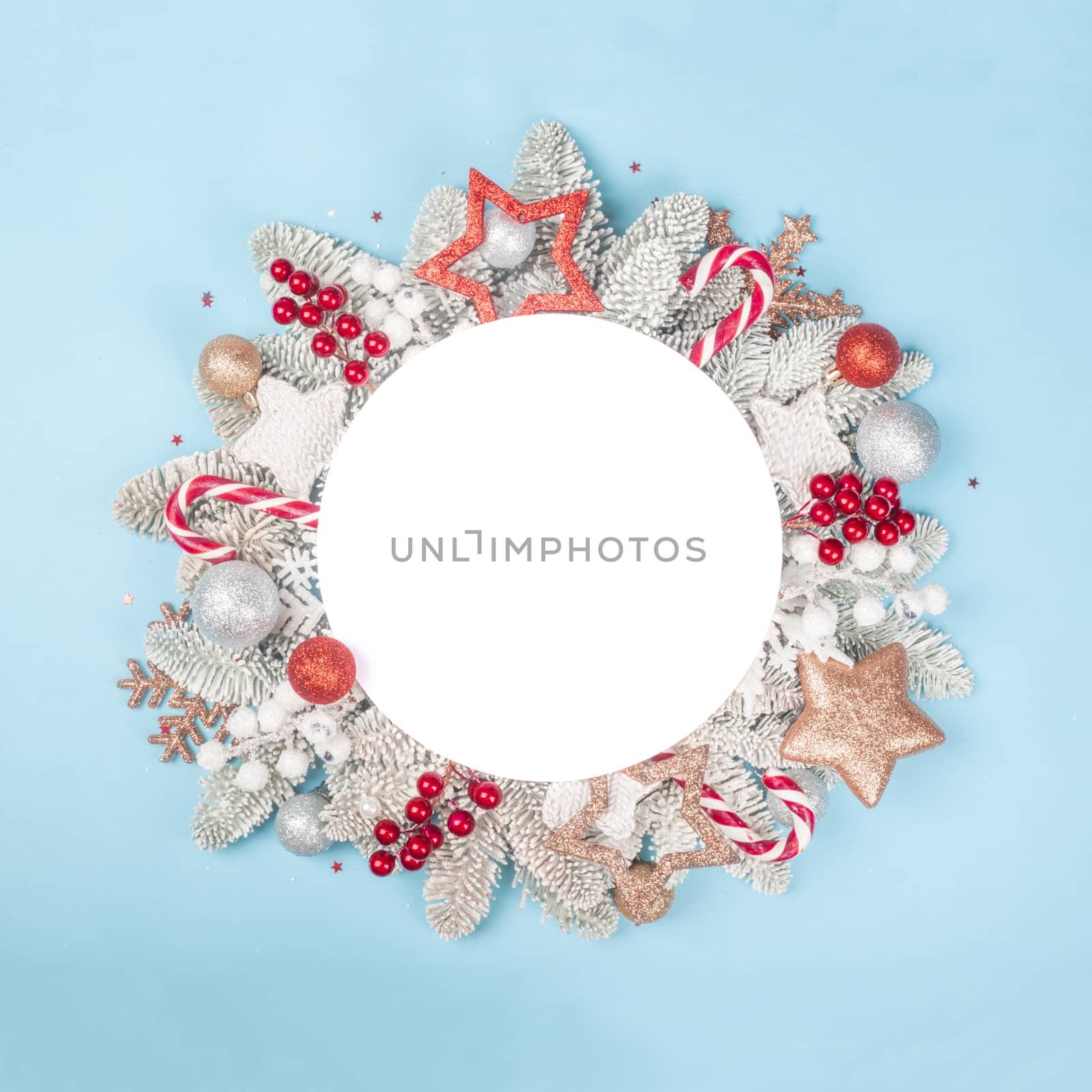 Frosted fir tree twigs and Christmas decorative bauble balls on blue background with white circle card with copy space for text template flat lay top view design