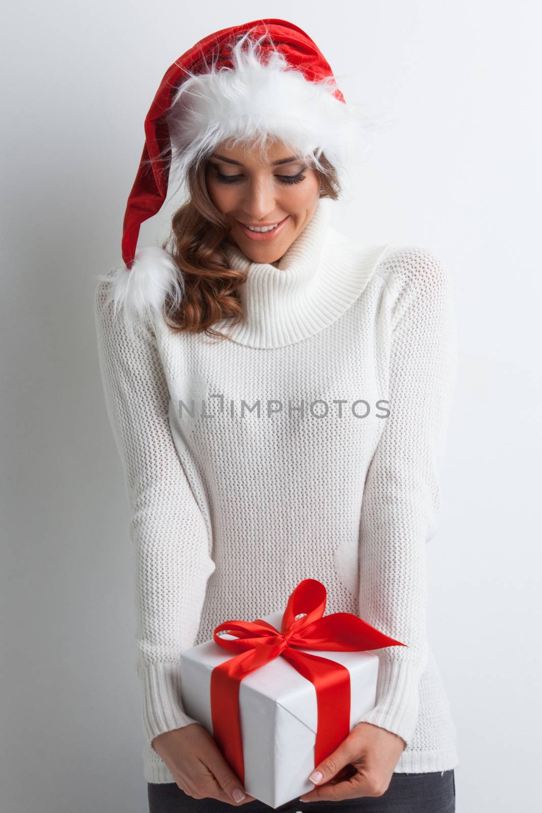 Smiling cute girl in Santa hat with red christmas gift box