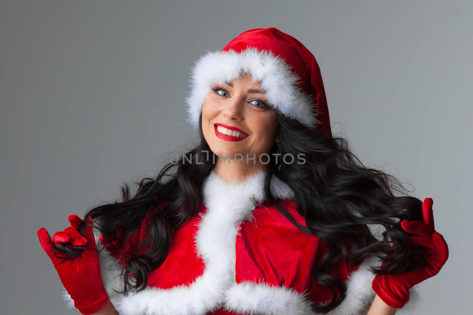 Portrait of a beautiful brunette woman wearing Santa's hat and costume show touch own hair