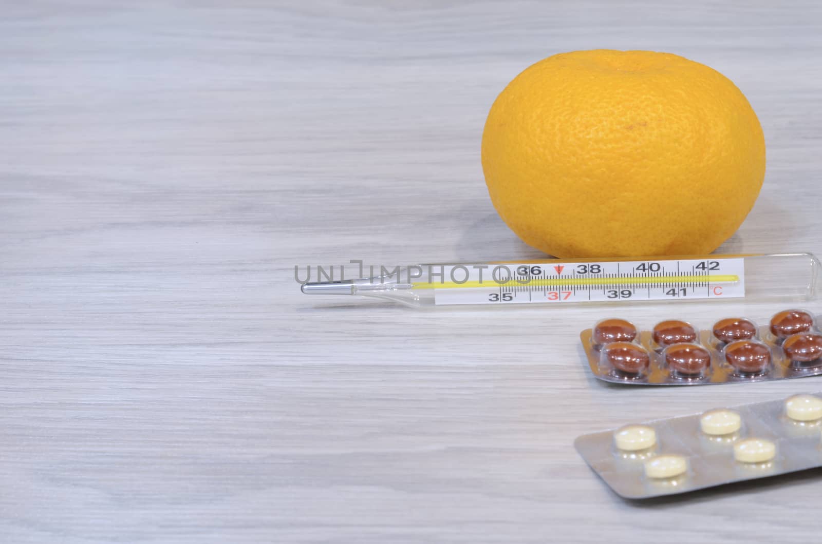 Cold thermometer pills. Flu cure, remedy for convalescence. Photo on a wooden background.