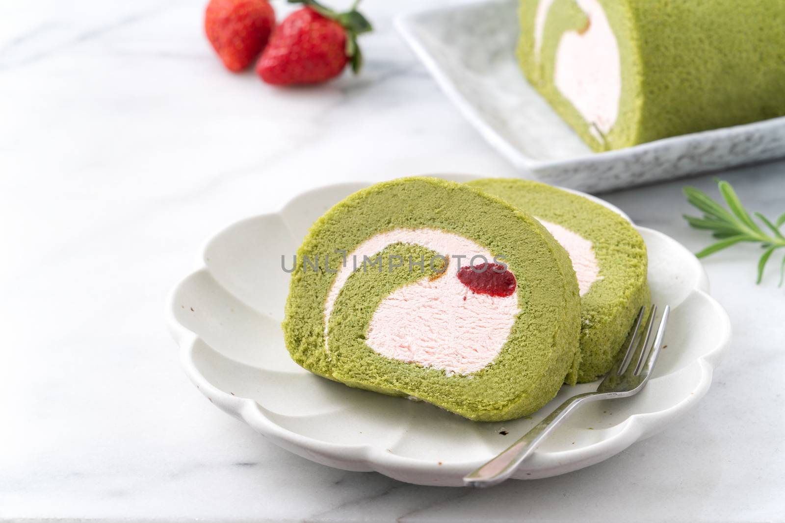 Delicious Matcha Swiss Roll Cake slices with strawberry icing cream on white background, close up.