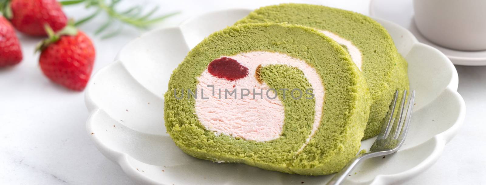 Delicious Matcha Swiss Roll Cake slices with strawberry icing cream on white background, close up.