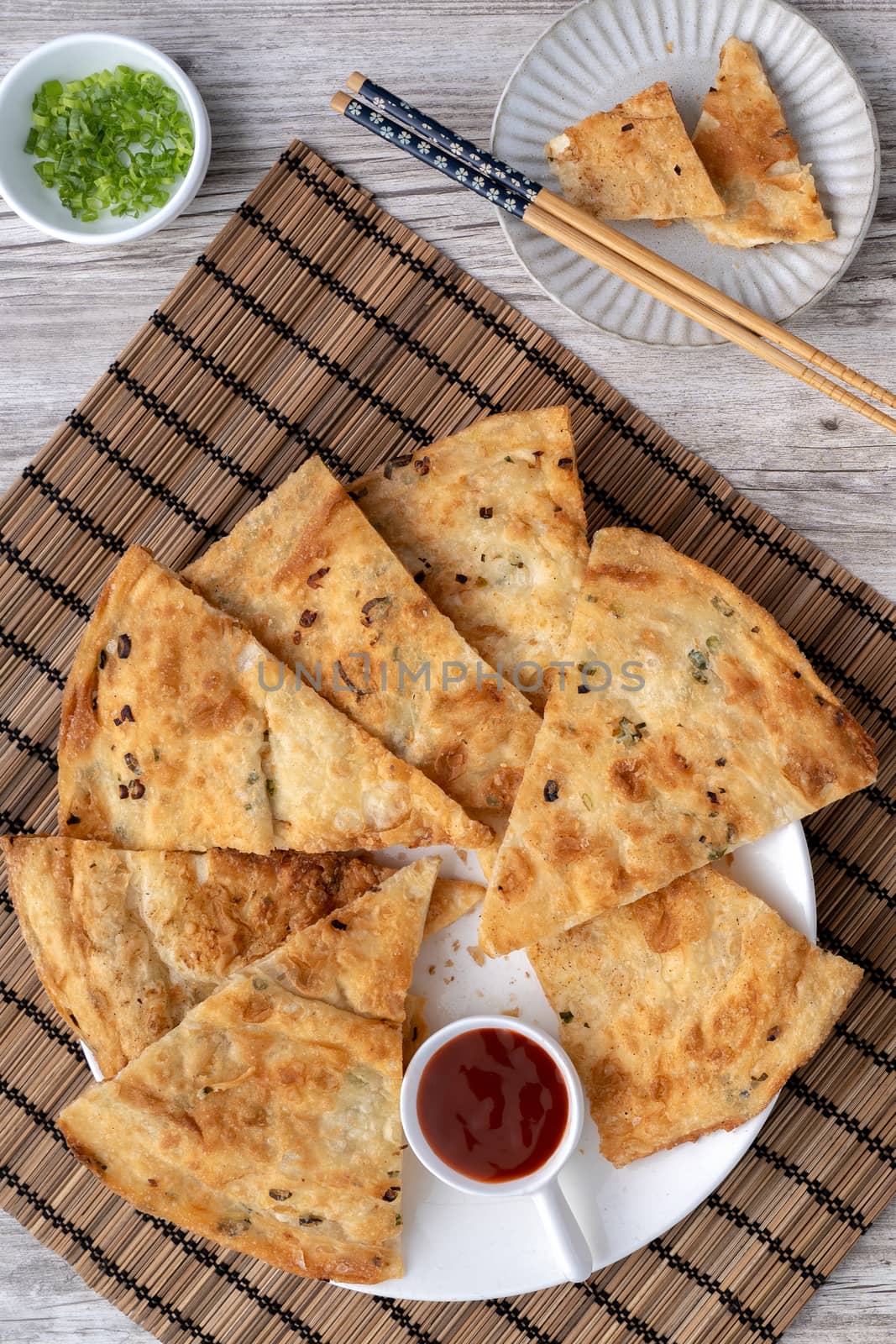 Taiwanese food - delicious flaky scallion pie pancakes on bright wooden table background, traditional snack in Taiwan, top view.