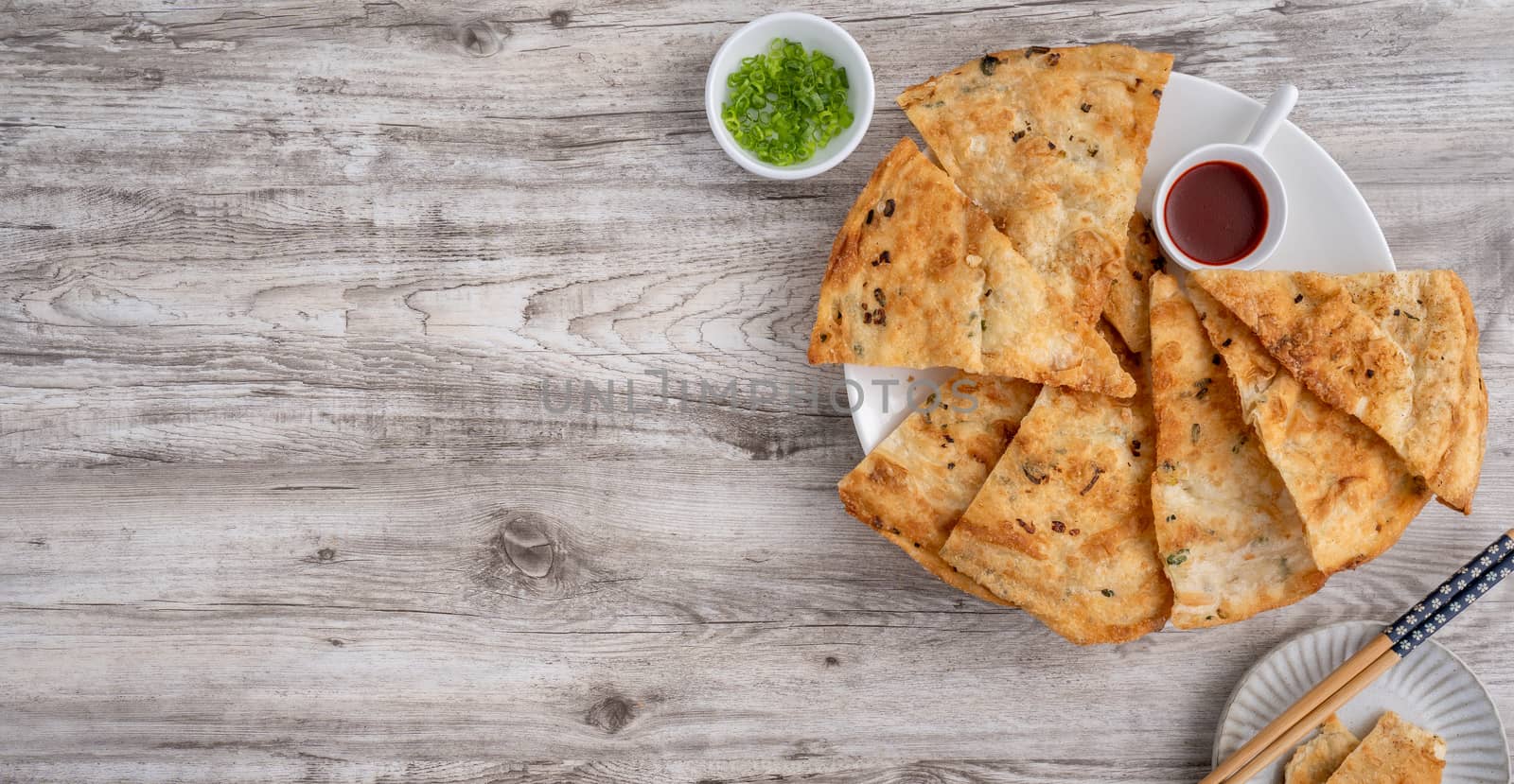 Taiwanese food - delicious flaky scallion pie pancakes on bright wooden table background, traditional snack in Taiwan, top view.