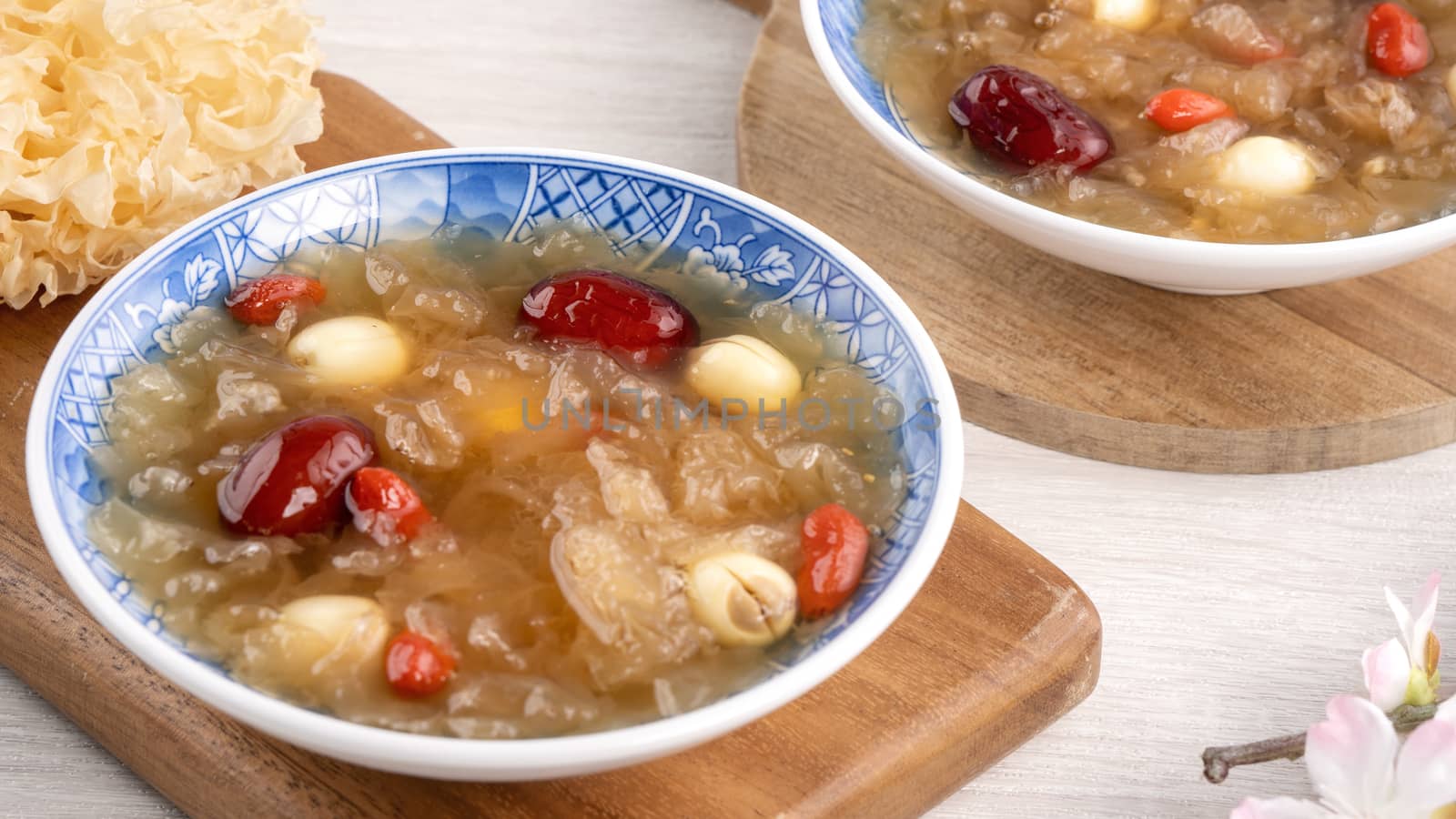 Close up of traditional Chinese sweet snow white fungus soup with lotus seed, red dates (jujube) and wolfberry (goji berry, gojiberry) on white background.