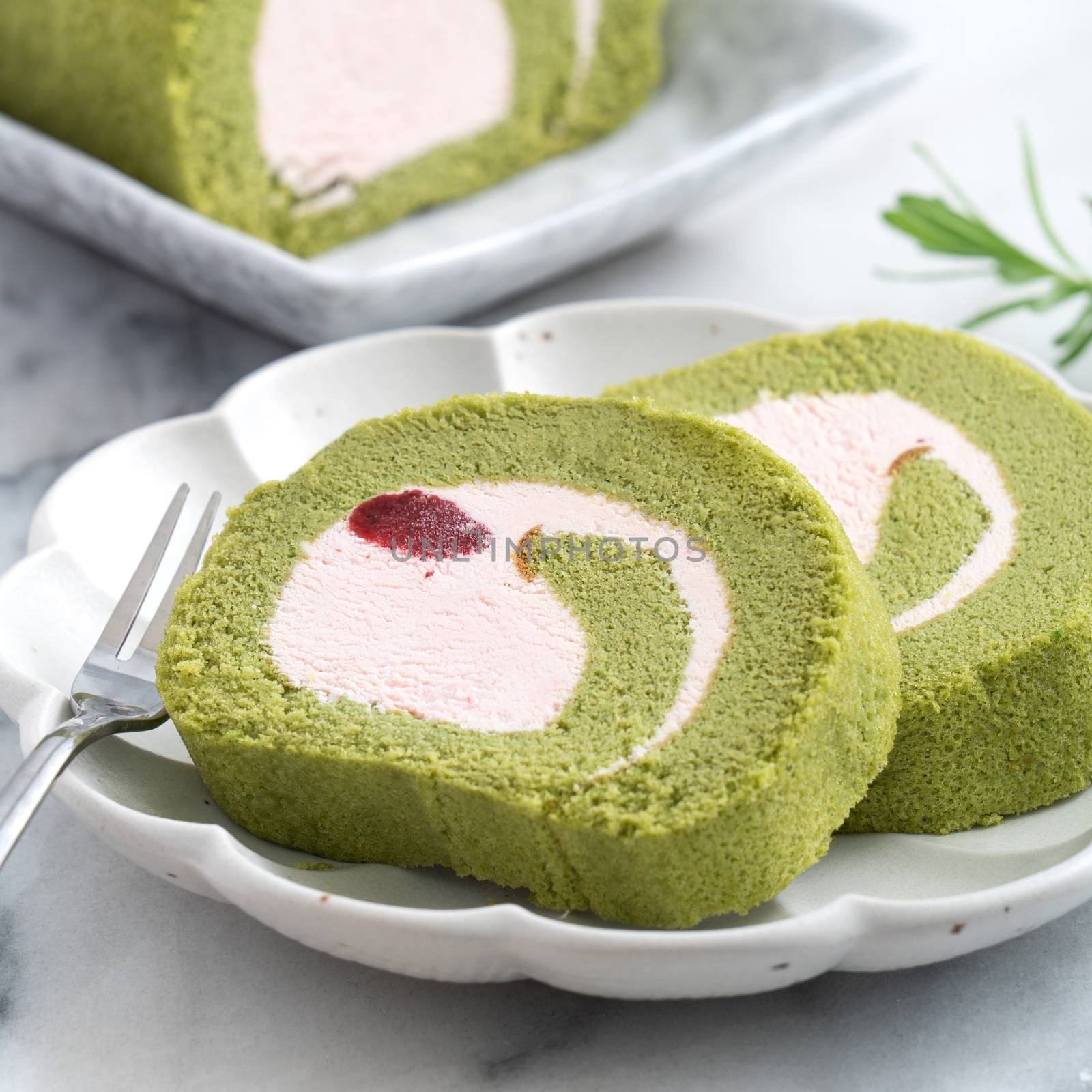 Delicious Matcha Swiss Roll Cake slices with strawberry icing cream on white background, close up.