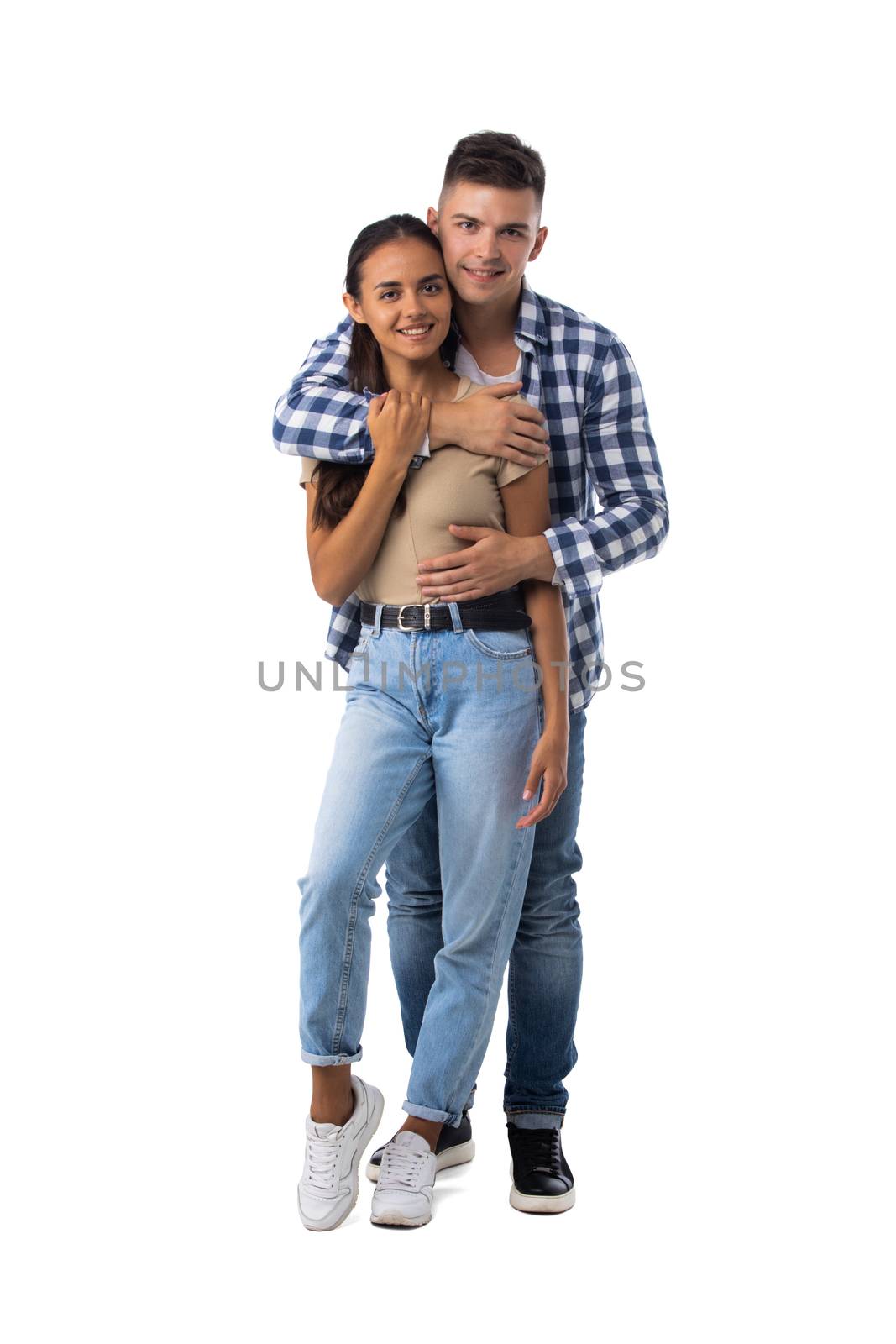 Smiling young couple embracing and standing full length isolated on white background