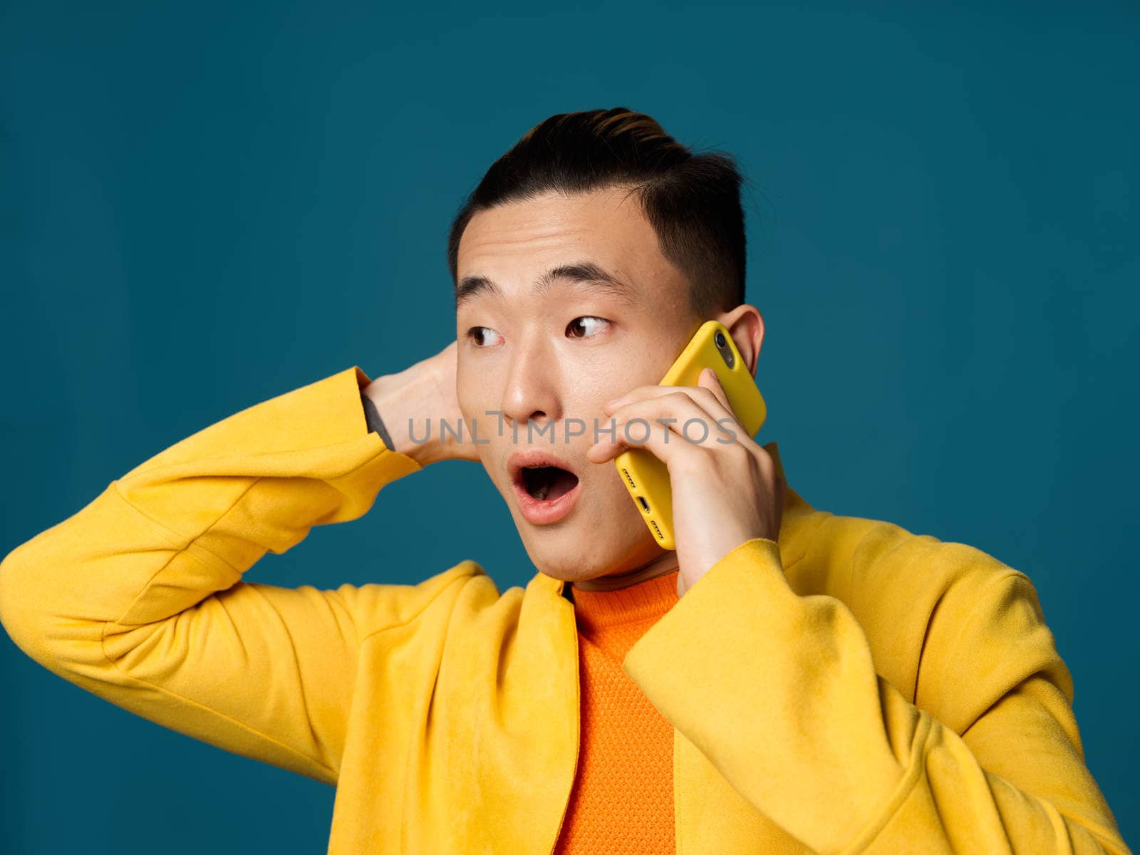 Man with open mouth on blue background talking on the phone cropped view of hand behind head. High quality photo