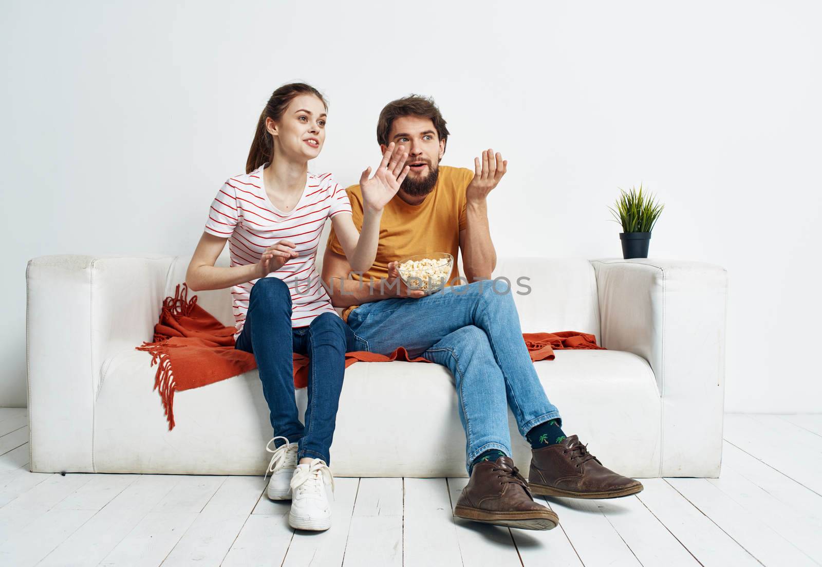 Pretty woman and bearded man watching TV on the sofa indoors. High quality photo