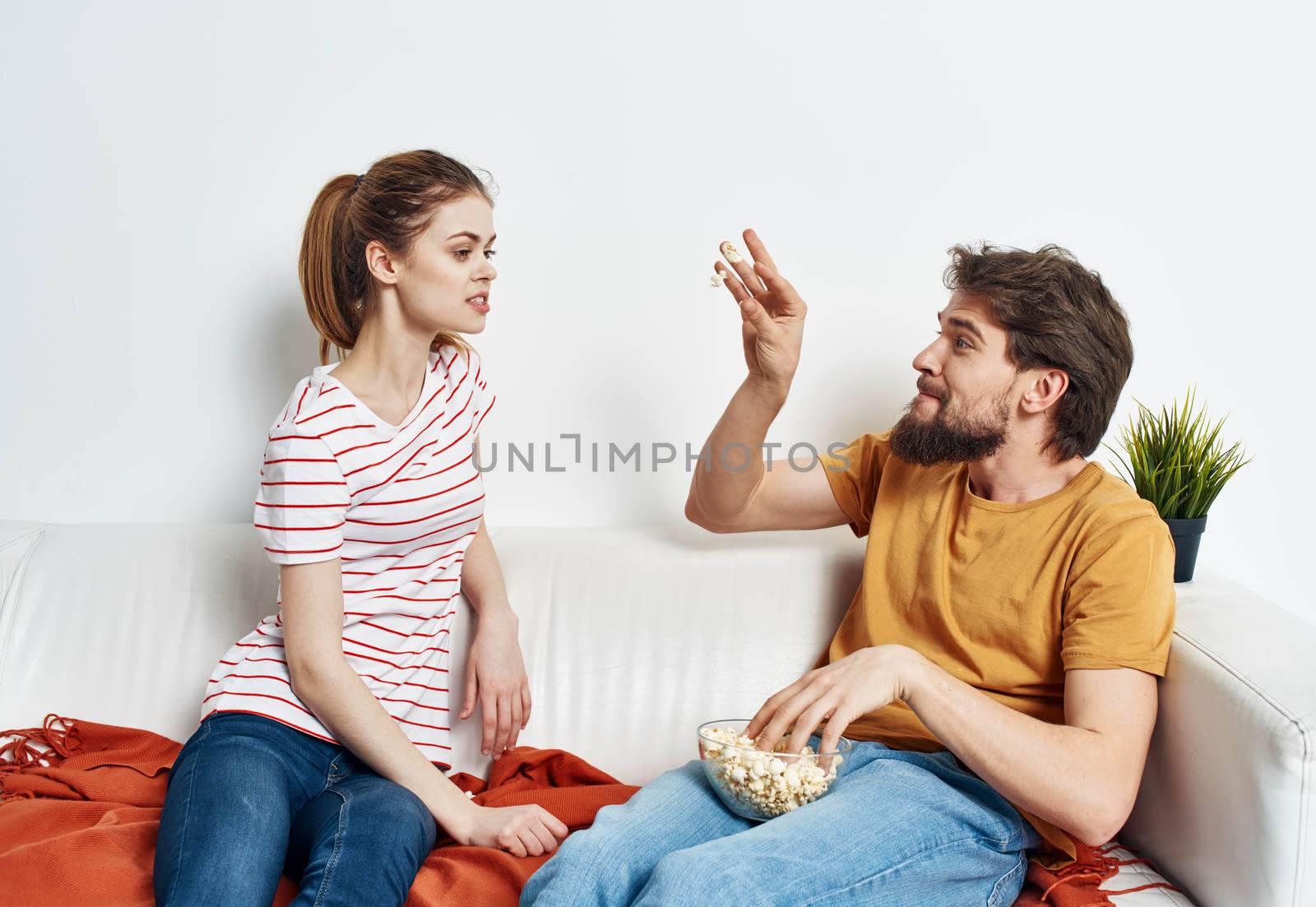 man and woman on the couch indoors chatting friends popcorn. High quality photo