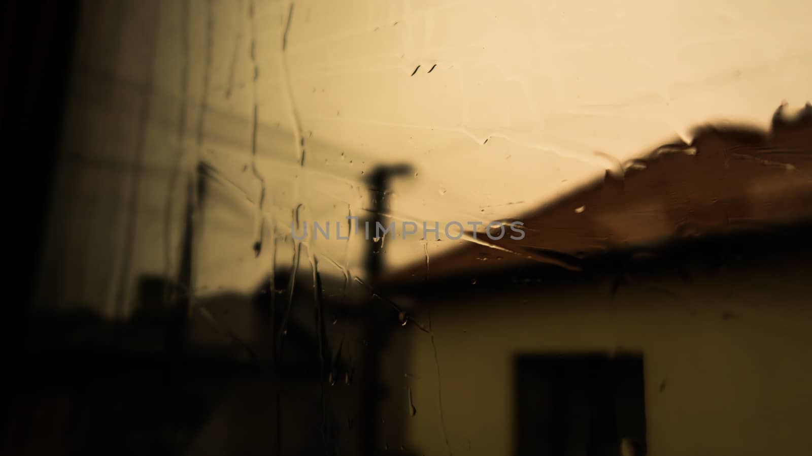 Water on the window. Rain on the window glass. Shadow on tree and nature through glass and rain. Shadow of house building by codrinn