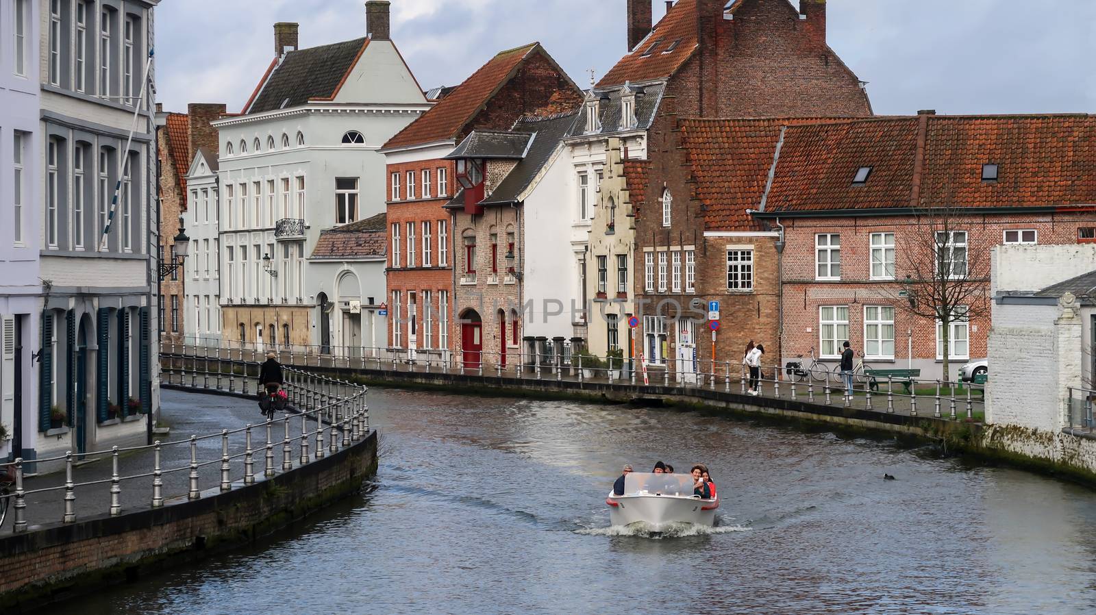 Bruges / Belgium - 03-08-2020: Boat with tourists on the canal and the buildings behind