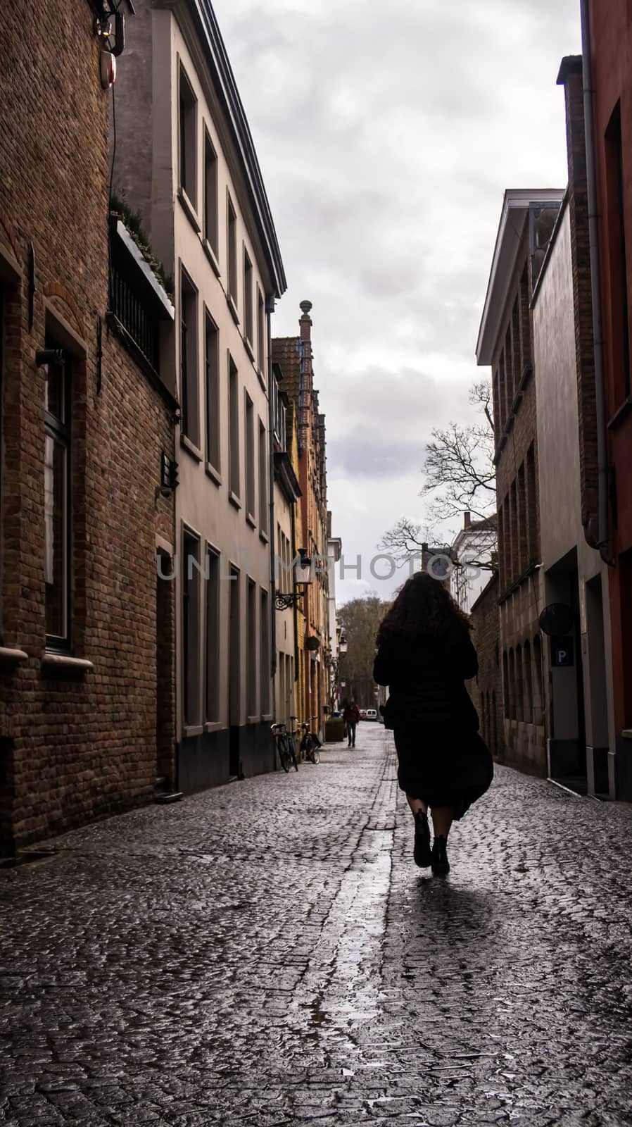 Silhouette woman walking in Bruges. Woman walking on the streets during a day with clouds on the sky.