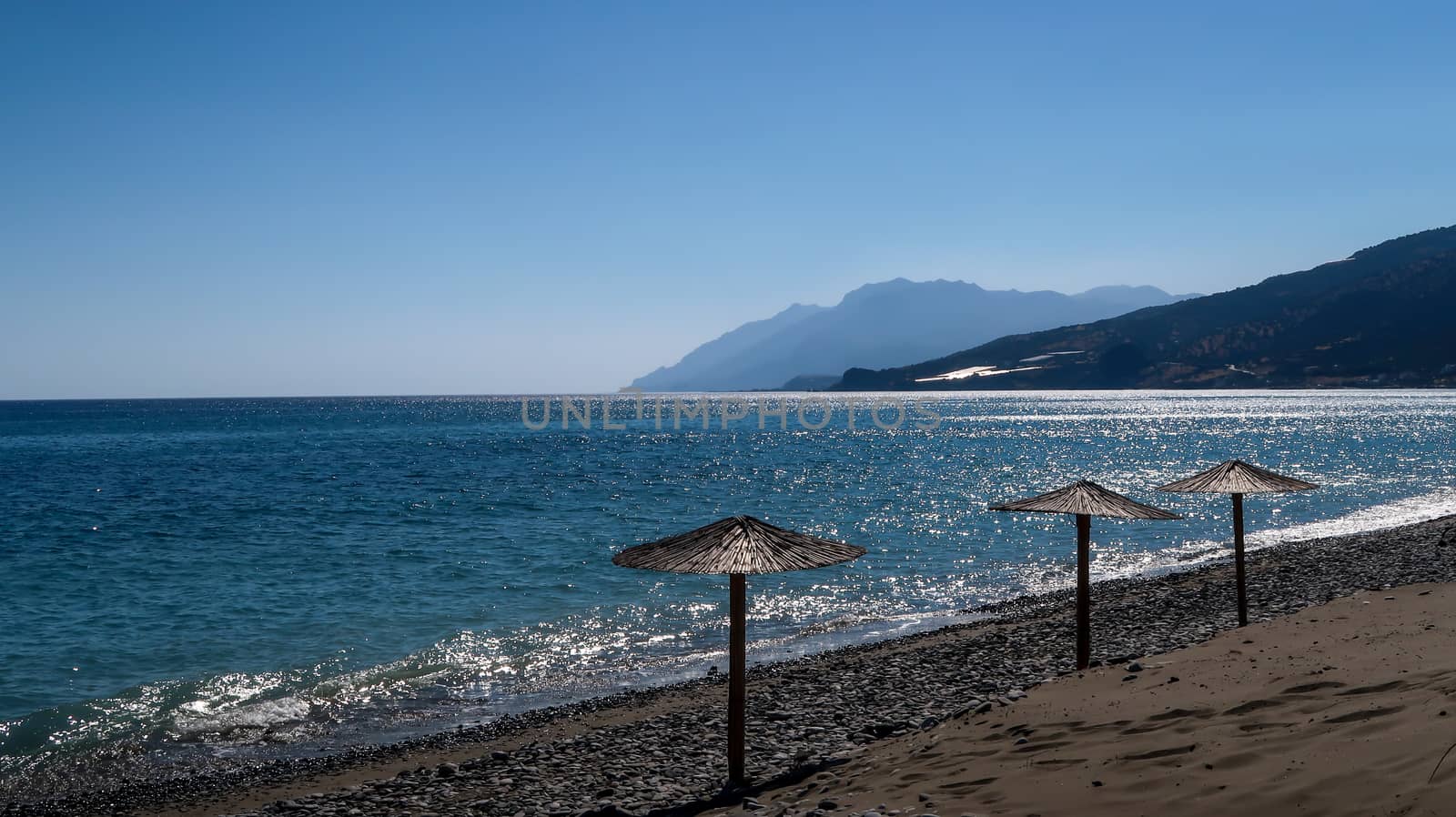 Hay umbrellas on the beach and mountains far away - Keratokampos, Crete by codrinn