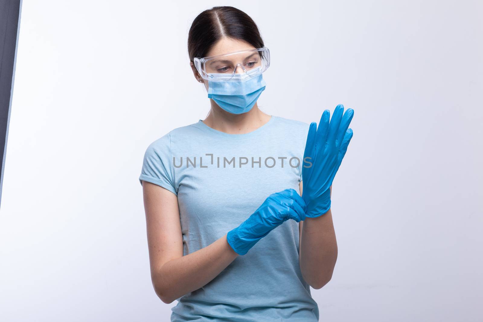 Nurse or doctor wearing and checking protective equipment agains by adamr