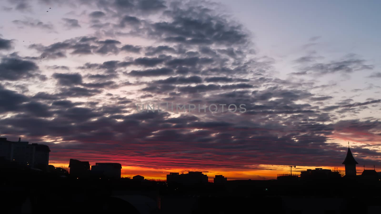 Cloudy fire sunrise with backlit buildings and cloudy sky. Landscape of fire sunrise