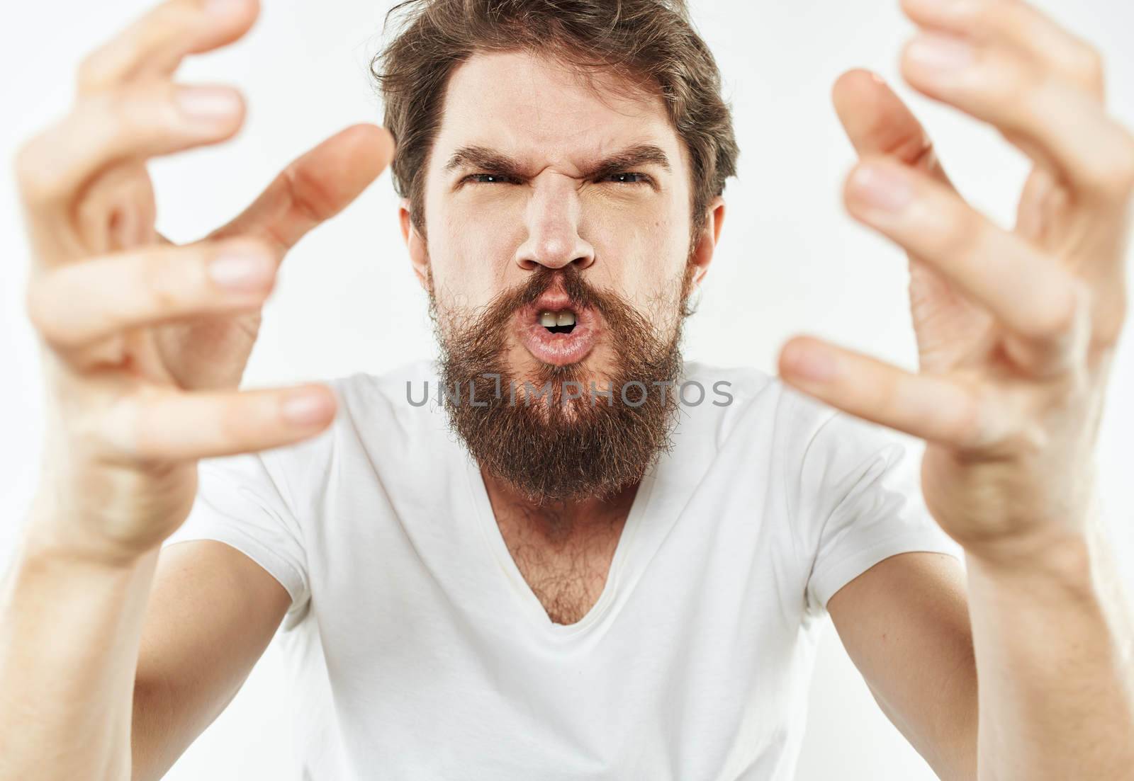 Emotional man on a white background in a T-shirt shows a gesture with his hands. High quality photo