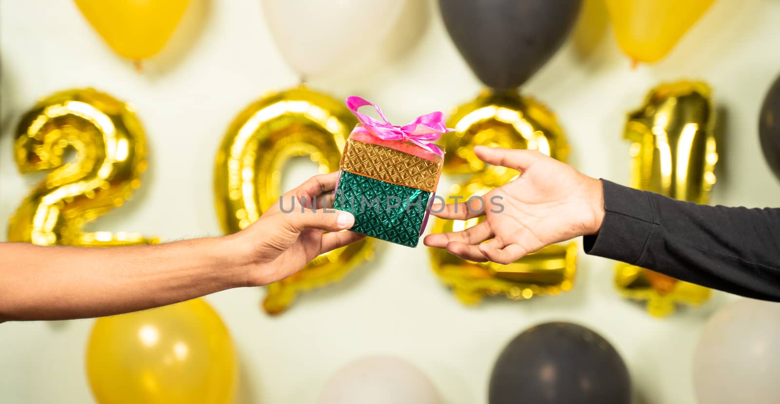 Close up of hands giving present gift box in 2021 new year celebration on decorated background - Concept of gift sharing on new year holydays