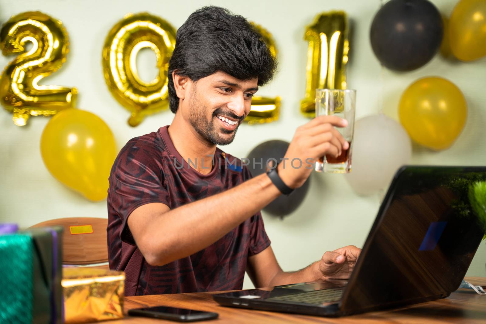 Young man partying during new year or Christmas celebration video call on laptop - concept of distant holyday celebration due to coronavirus or covid-19 pandemic. by lakshmiprasad.maski@gmai.com